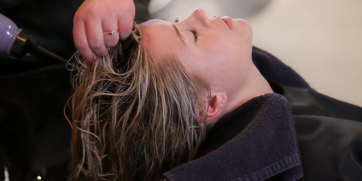 A women receiving a hair slugging treatment over a washbasin