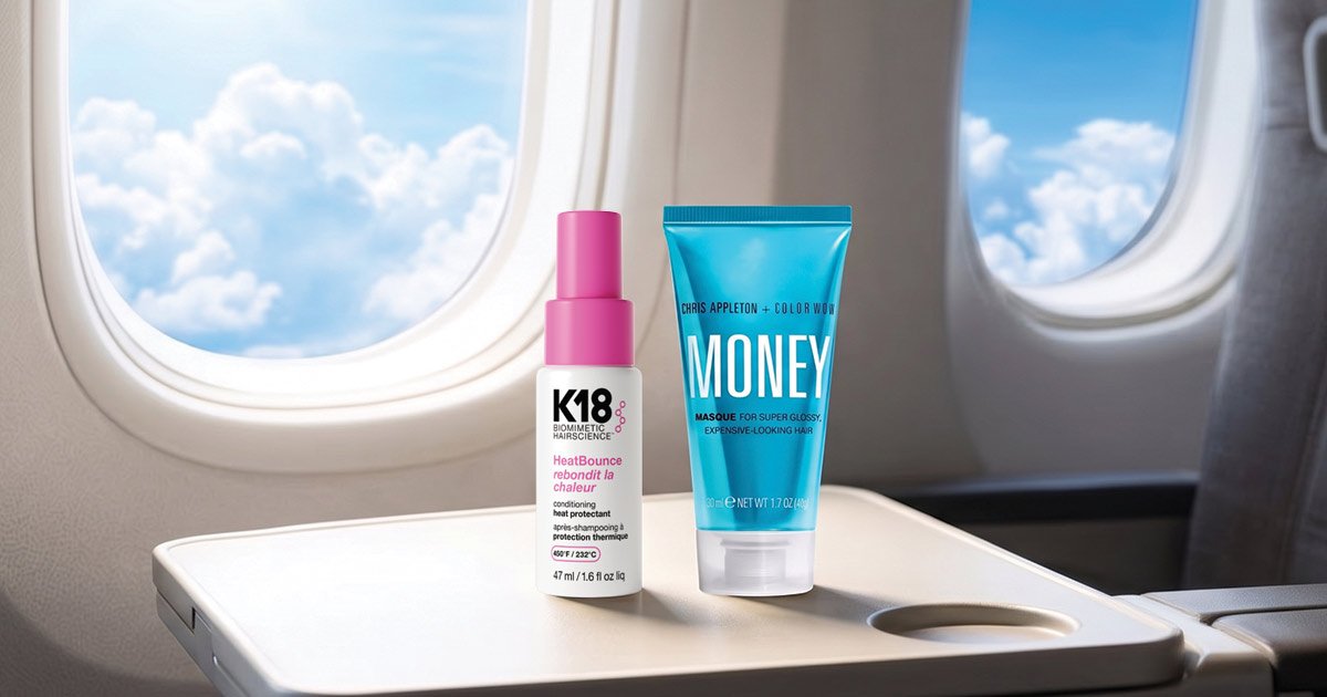 Two travel-sized hair care products, a K18 HeatBounce spray and a Chris Appleton + Color Wow Money Masque tube, standing on an airplane tray table next to a window showing a bright blue sky and white clouds.