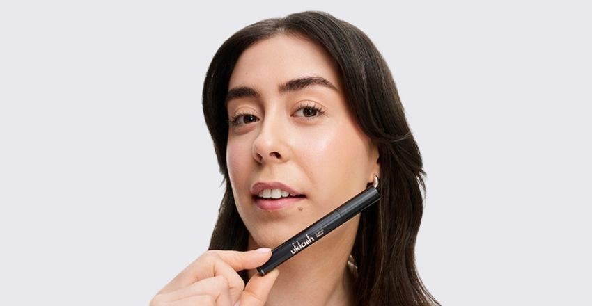 A woman holding the UKLASH Eyelash Growth Serum